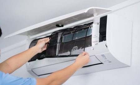 Man’s Hands Replacing Air Conditioner Filter In A Home With Precision And Care.