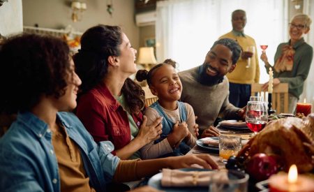 A family celebrating the holiday season sits together to enjoy a festive meal, unaware that their indoor air quality is plummeting.