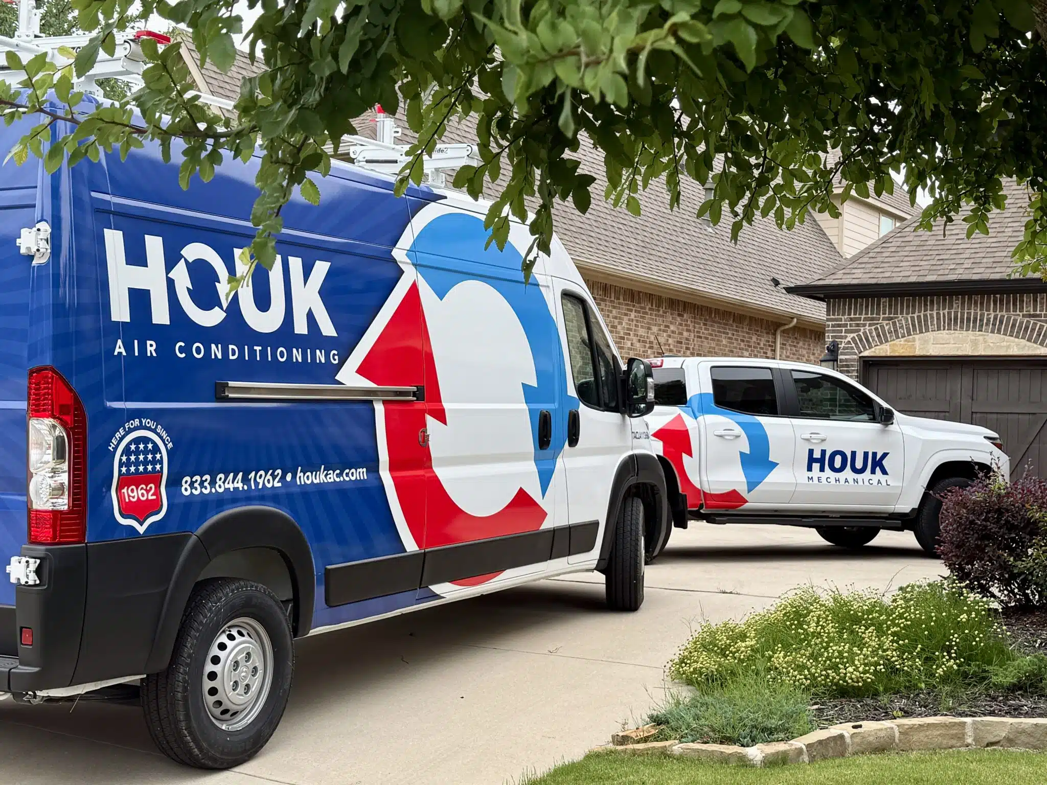 Houk AC service vehicles outside Dallas-Fort Worth home during a Helping Hands HVAC installation.