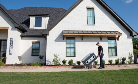 HVAC installer in front of a white house with a new AC