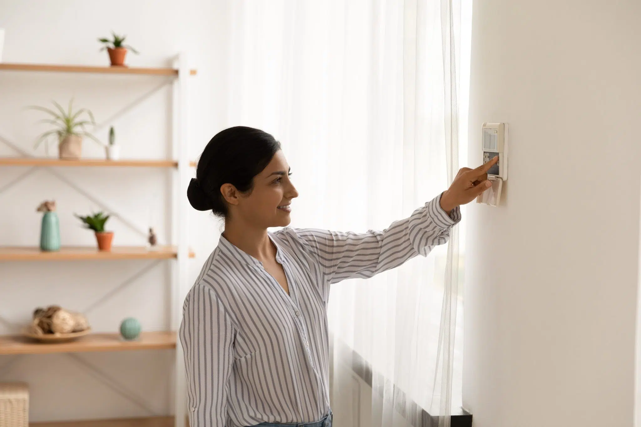 DFW homeowner adjusts her thermostat from heat to cool during a warm spring day in North Texas.