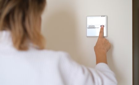 A DFW homeowner adjusting her thermostat to cool her home during spring weather.