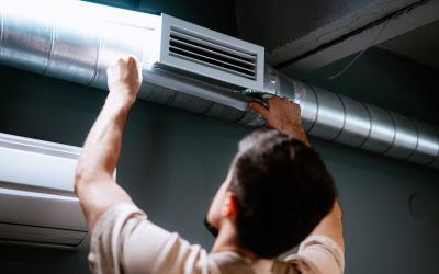 An HVAC technician inspects the air duct and vent register on the ceiling of a DFW home.