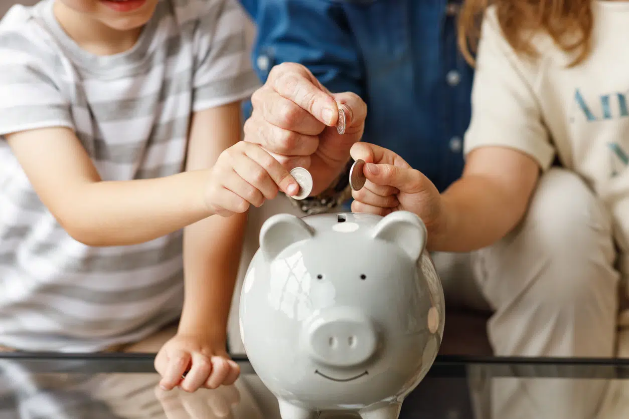 Children and a parent saving coins in a piggy bank, a nod to the money DFW homeowners keep with smart HVAC maintenance tips.