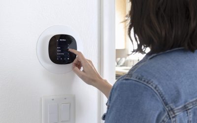 DFW homeowner adjusting smart thermostat settings before leaving for vacation.
