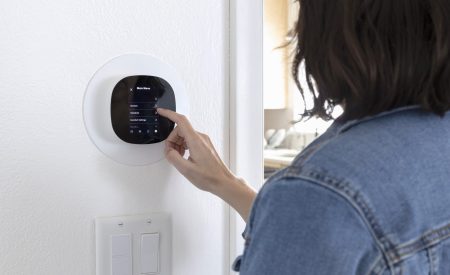 DFW homeowner adjusting smart thermostat settings before leaving for vacation.