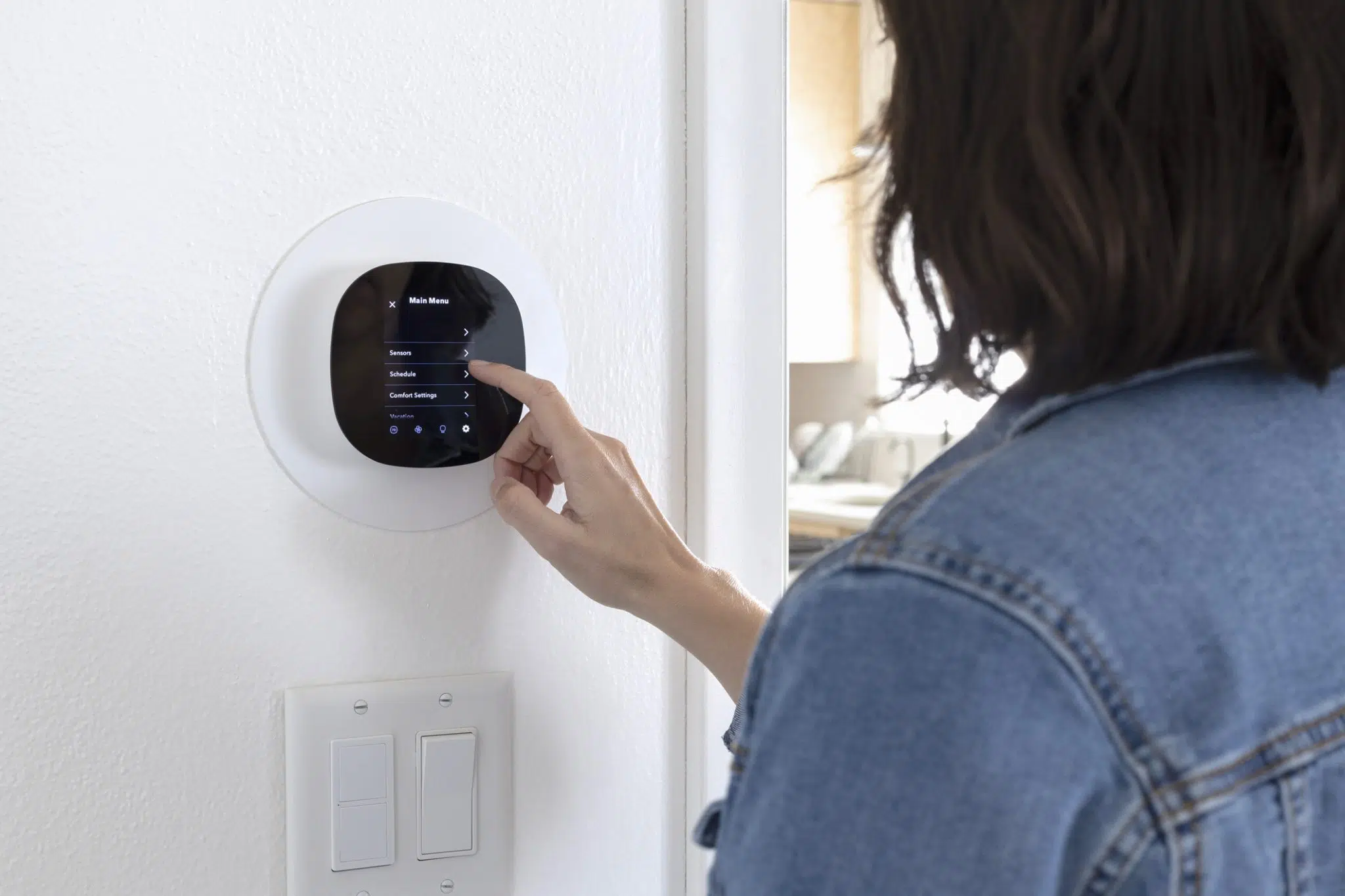 DFW homeowner adjusting smart thermostat settings before leaving for vacation.