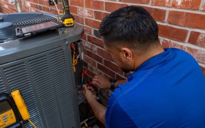 Houk technician performing preventive HVAC service on a central AC unit outside a DFW brick home.