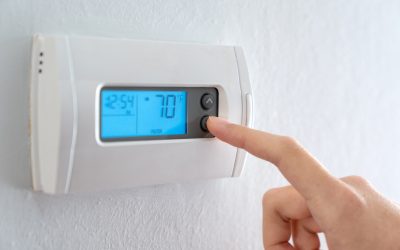 Hand adjusting a home thermostat set to 70°F during an ERCOT conservation alert in Texas.