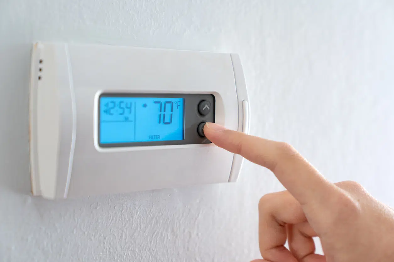 Hand adjusting a home thermostat set to 70°F during an ERCOT conservation alert in Texas.