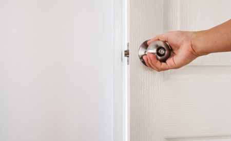 A hand closing a white interior bedroom door, the everyday habit that can restrict a home's airflow