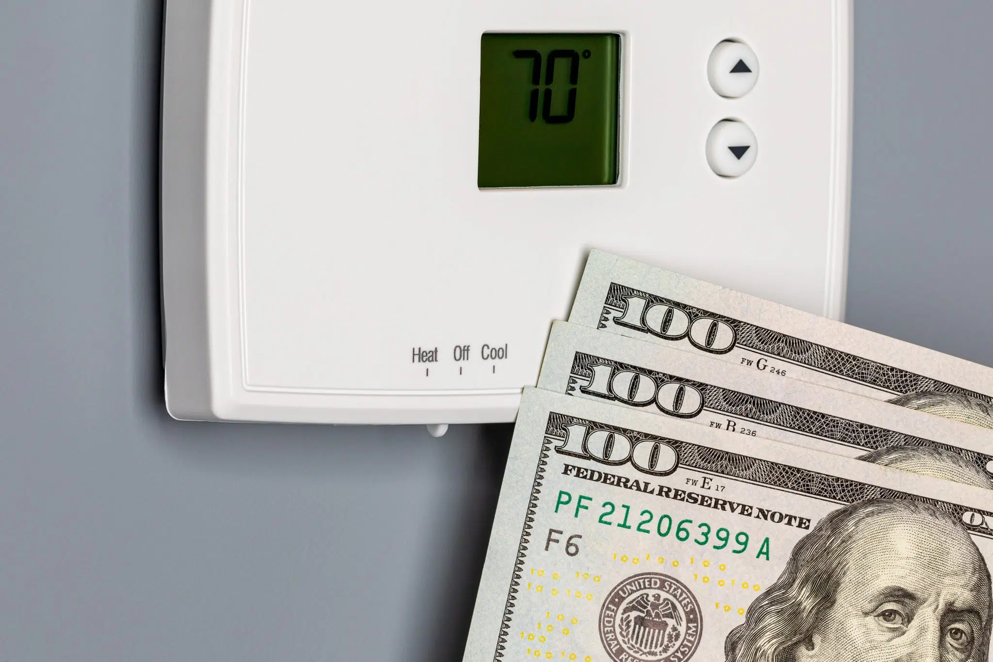 Cash tucked beside a home thermostat, representing what HVAC installation and AC replacement can cost DFW homeowners.