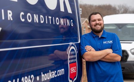 Houk Air Conditioning technician beside a branded van before an HVAC consultation