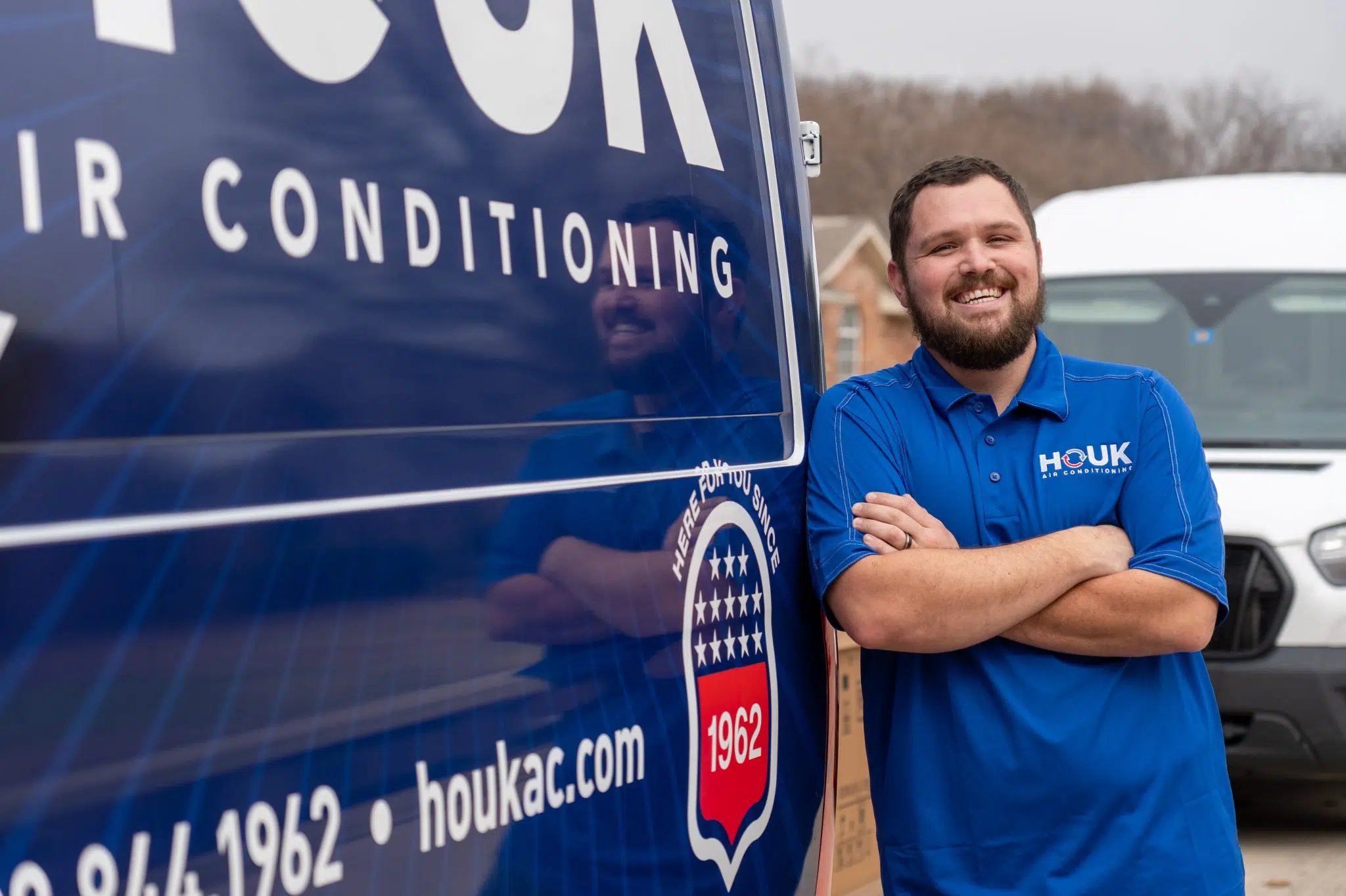 Houk Air Conditioning technician beside a branded van before an HVAC consultation