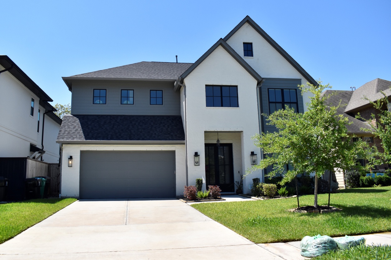 Two-story new build with white brick and gray siding, typical of new construction HVAC homes in Frisco and North Dallas.